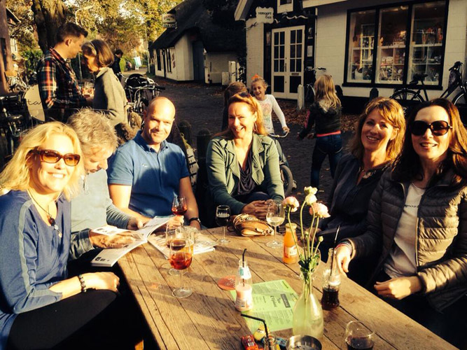 Gasten aan een lange tafel op het terras, met de kaart erbij.