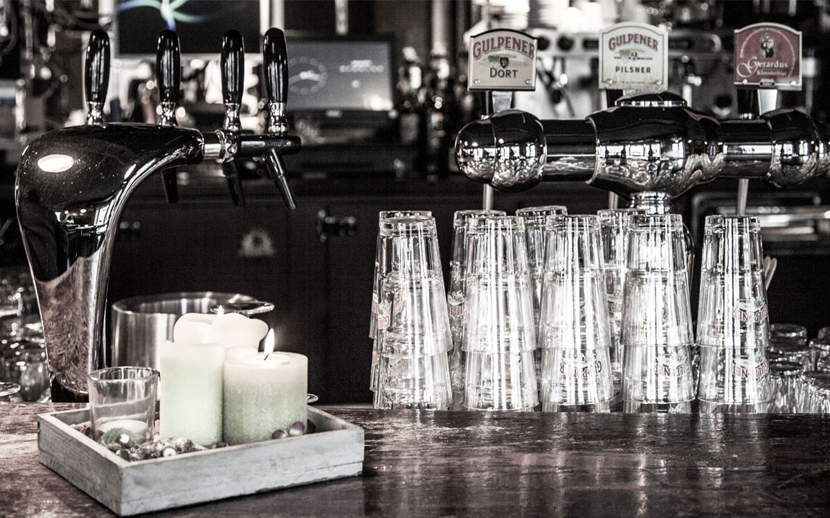 De tap van de Taverne met schoongespoelde bierglazen en kaarsen op de bar